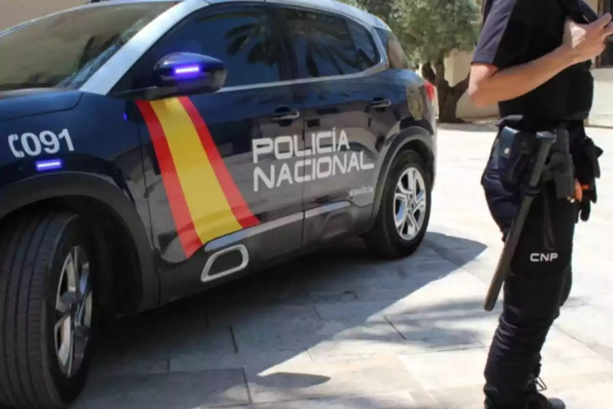 National Police of Spain patrol with an official car and an officer standing next to the vehicle