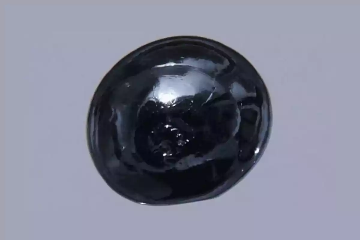 Shiny black rounded stone on a light gray background Shiny black rounded stone on a light gray background