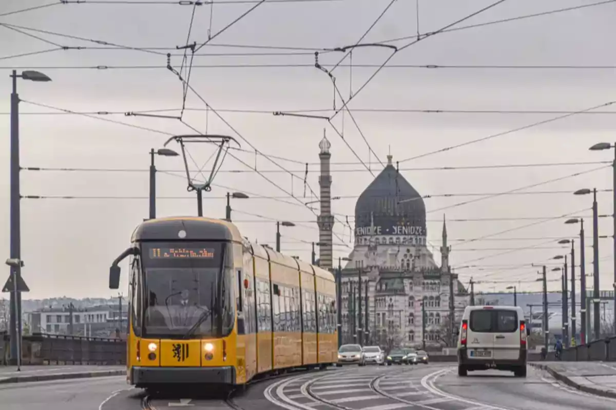 Yellow tram crossing a bridge in a European city with a blue-domed building in the background and a cloudy sky. Yellow tram crossing a bridge in a European city with a blue-domed building in the background and a cloudy sky.