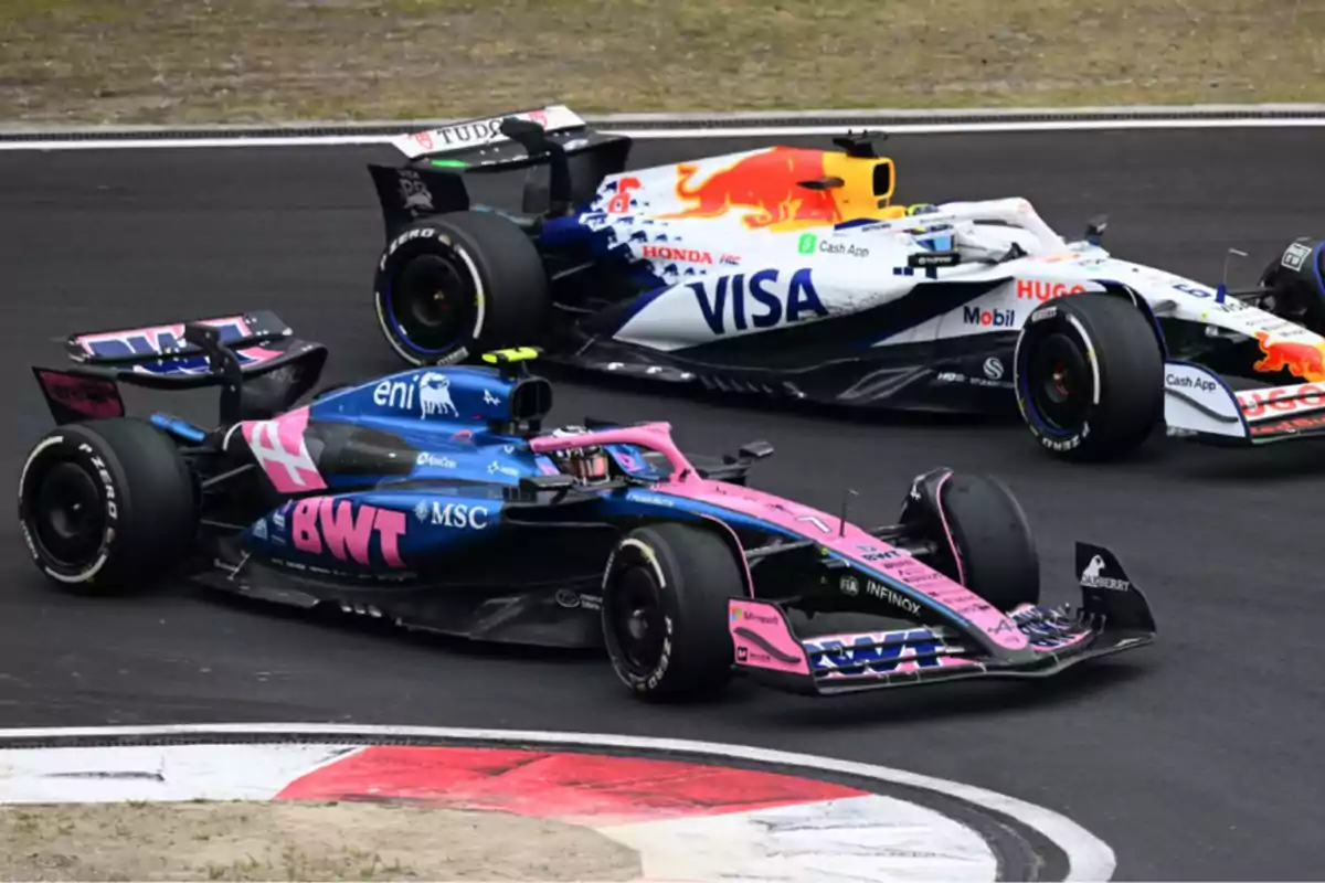 Dos autos de Fórmula 1 compitiendo en una curva durante una carrera en pista asfaltada Dos autos de Fórmula 1 compitiendo en una curva durante una carrera en pista asfaltada