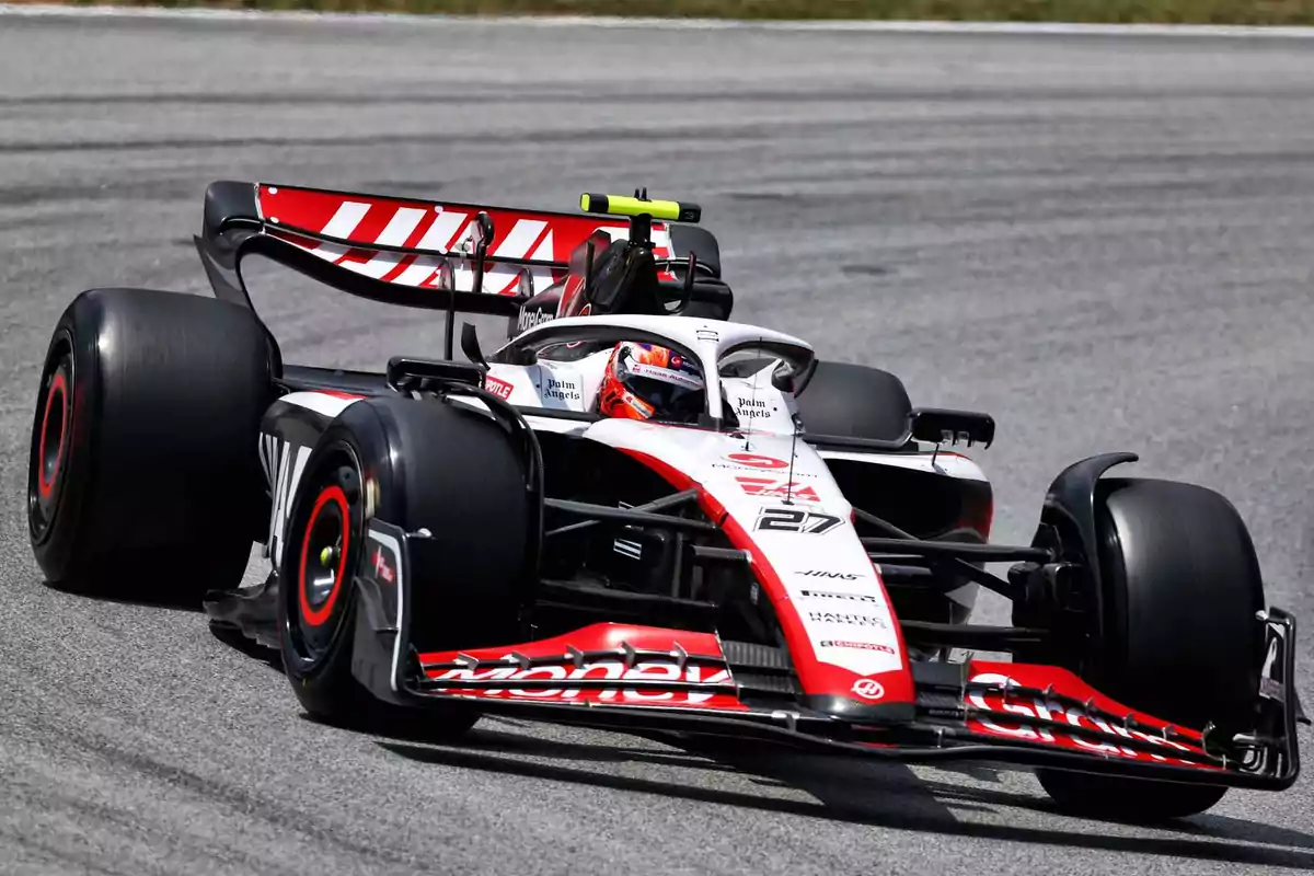 Haas Formula 1 single-seater taking a corner during a race on an asphalt track Haas Formula 1 single-seater taking a corner during a race on an asphalt track
