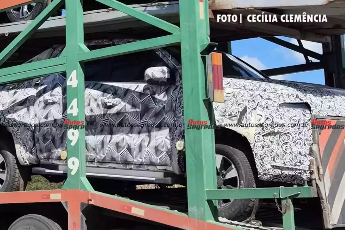 Camioneta cubierta con camuflaje de pruebas siendo transportada en un remolque verde Camioneta cubierta con camuflaje de pruebas siendo transportada en un remolque verde