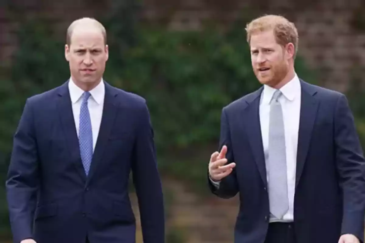Two men dressed in dark suits and ties walk together outdoors while talking. Two men dressed in dark suits and ties walk together outdoors while talking.