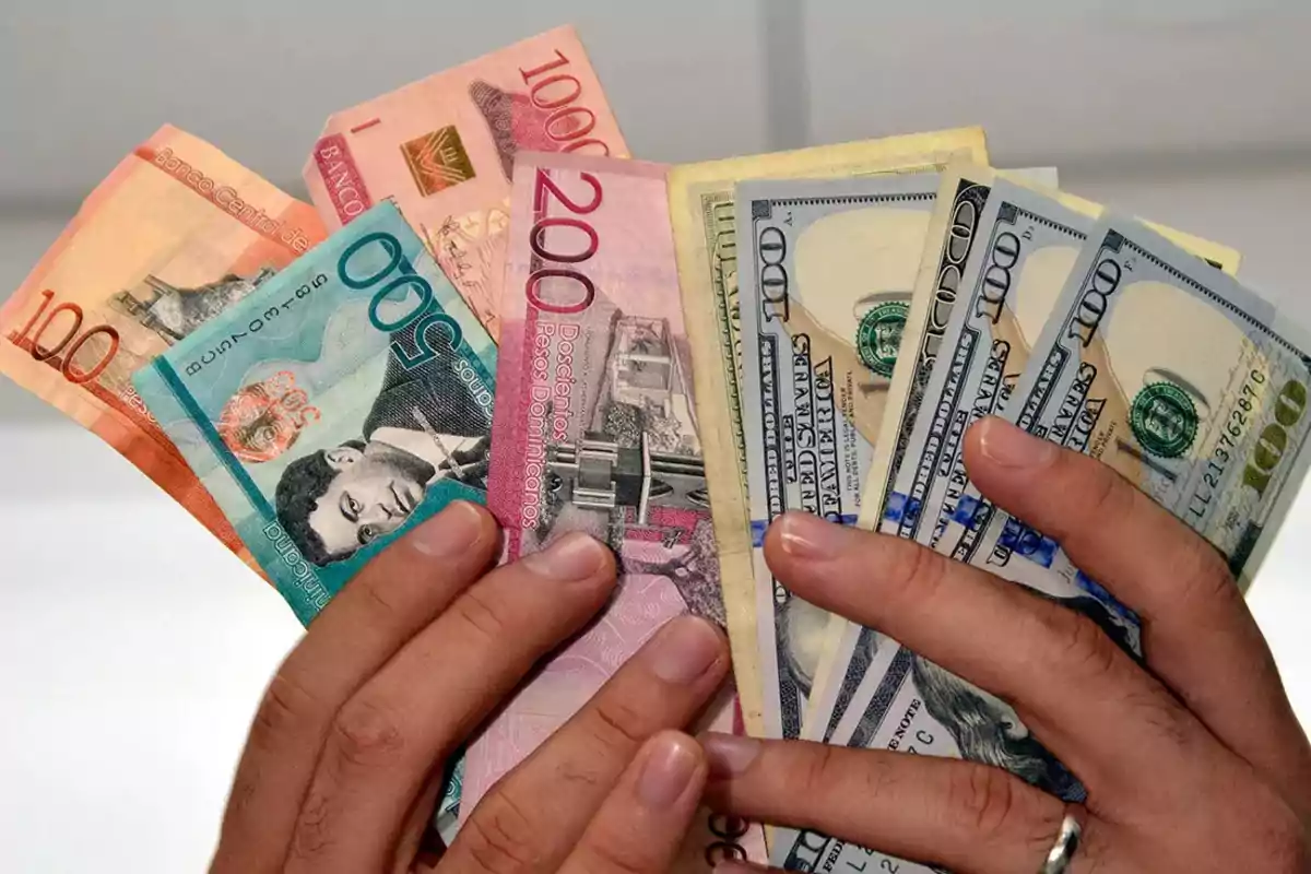 Manos sosteniendo billetes de pesos dominicanos y dólares estadounidenses Manos sosteniendo billetes de pesos dominicanos y dólares estadounidenses