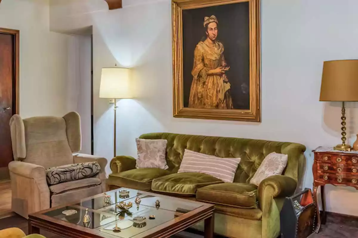 Living room with beige armchair, green sofa with cushions, glass coffee table, lamps, and an antique painting of a woman on the wall Living room with beige armchair, green sofa with cushions, glass coffee table, lamps, and an antique painting of a woman on the wall