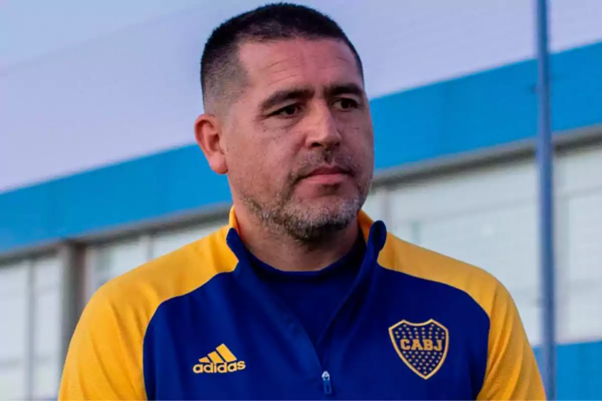 Man wearing a blue and yellow Boca Juniors jacket standing in front of a building Man wearing a blue and yellow Boca Juniors jacket standing in front of a building