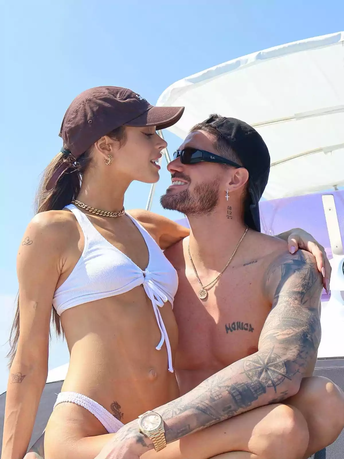 Pareja joven en traje de baño disfrutando juntos en un yate bajo el sol Pareja joven en traje de baño disfrutando juntos en un yate bajo el sol