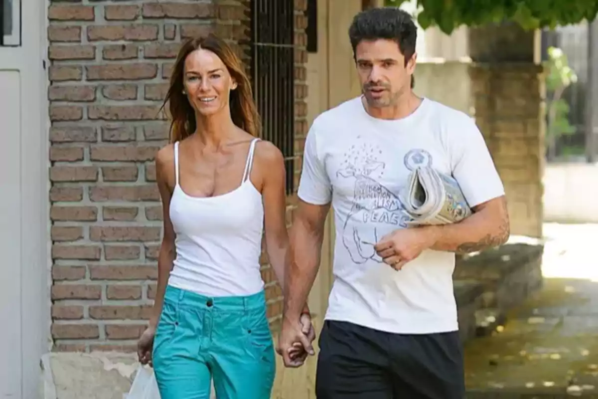 Una pareja camina de la mano por la calle en un día soleado, ambos visten ropa casual y parecen relajados. Una pareja camina de la mano por la calle en un día soleado, ambos visten ropa casual y parecen relajados.