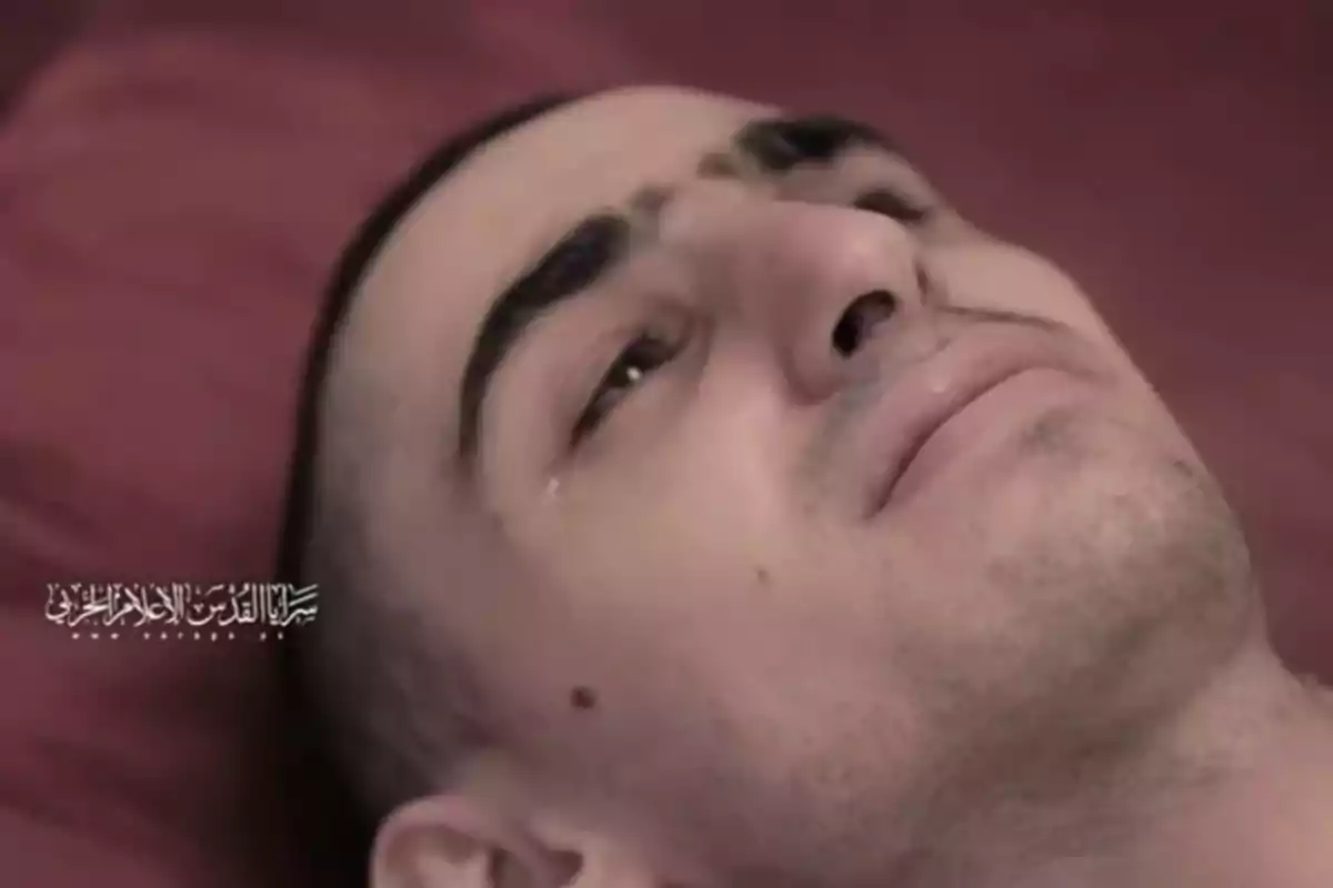 Man lying on a red surface with a tear on his cheek and a serious expression Man lying on a red surface with a tear on his cheek and a serious expression