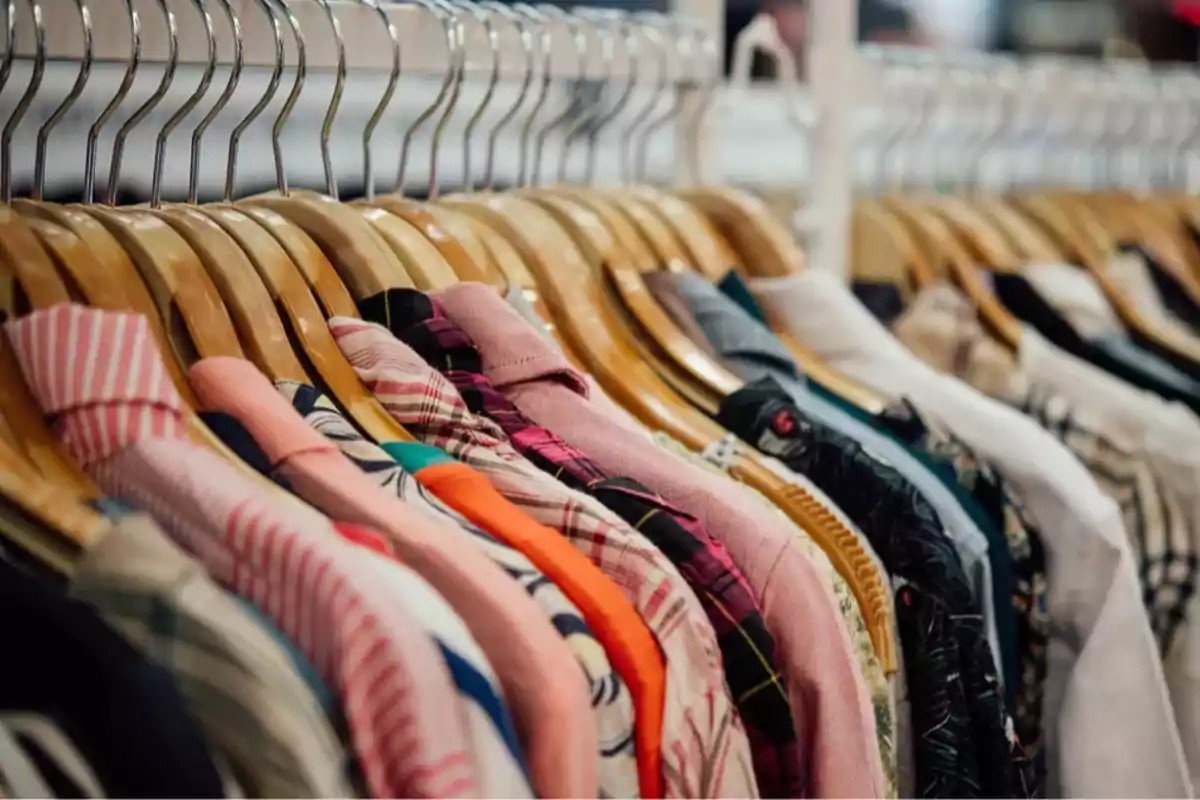 Camisas de diferentes colores y estampados colgadas en perchas de madera en una tienda de ropa Camisas de diferentes colores y estampados colgadas en perchas de madera en una tienda de ropa