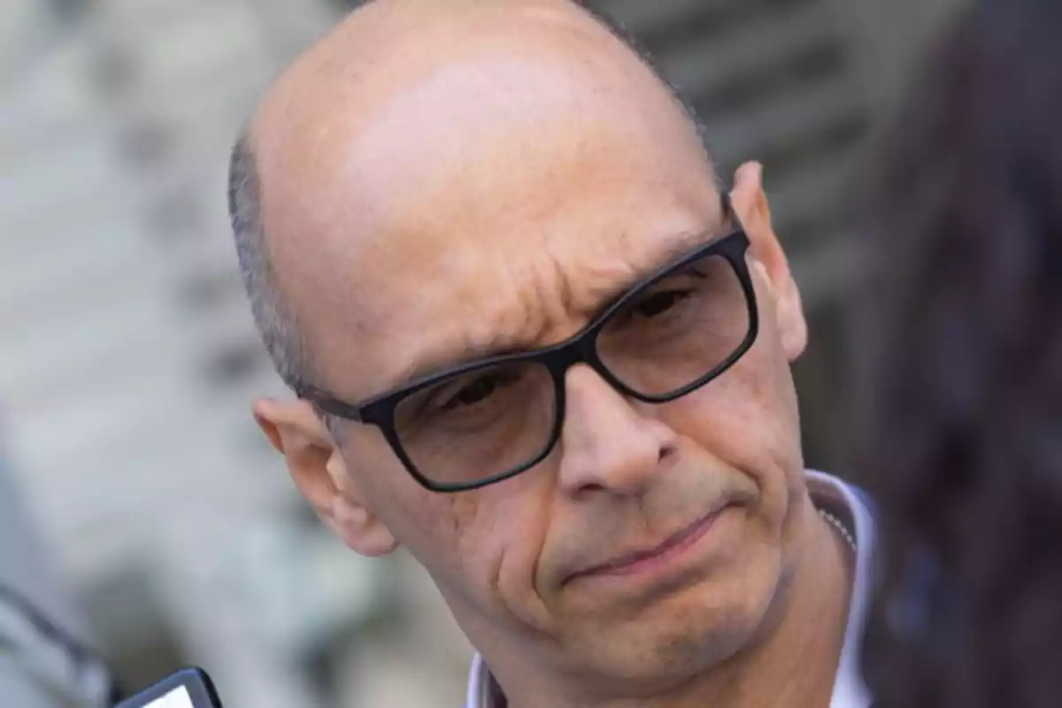 Bald man with black glasses looking straight ahead with a serious expression Bald man with black glasses looking straight ahead with a serious expression
