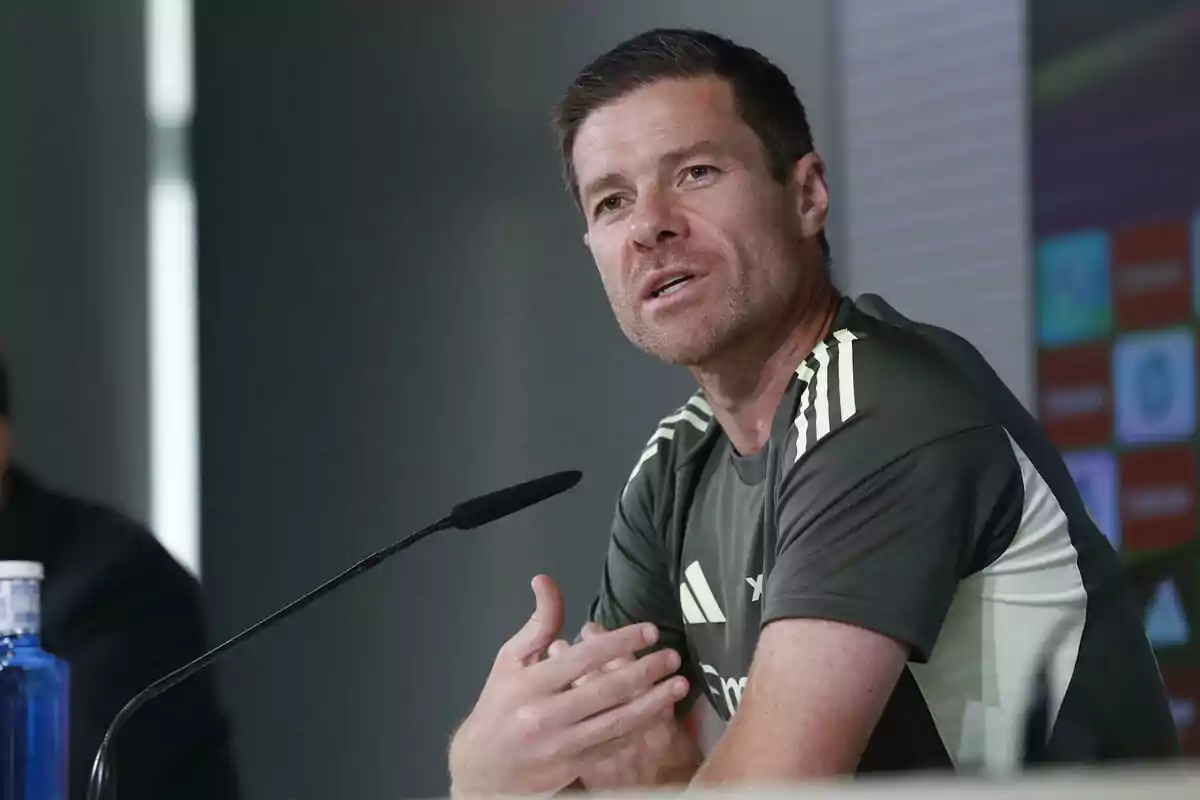 Man in a sports jersey speaking at a press conference in front of a microphone Man in a sports jersey speaking at a press conference in front of a microphone