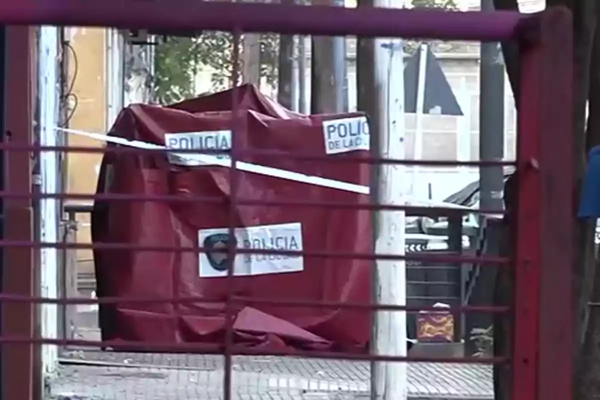 Scene cordoned off by the police with a red tarp covering an area on the public road