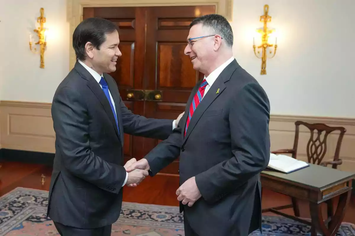 Two men in suits greet each other with a handshake in an elegant office. Two men in suits greet each other with a handshake in an elegant office.