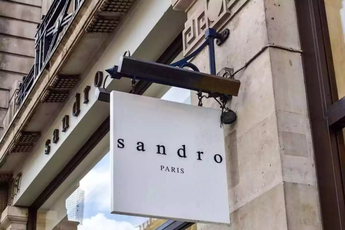 Letrero de la tienda Sandro Paris colgado en la fachada de un edificio de piedra