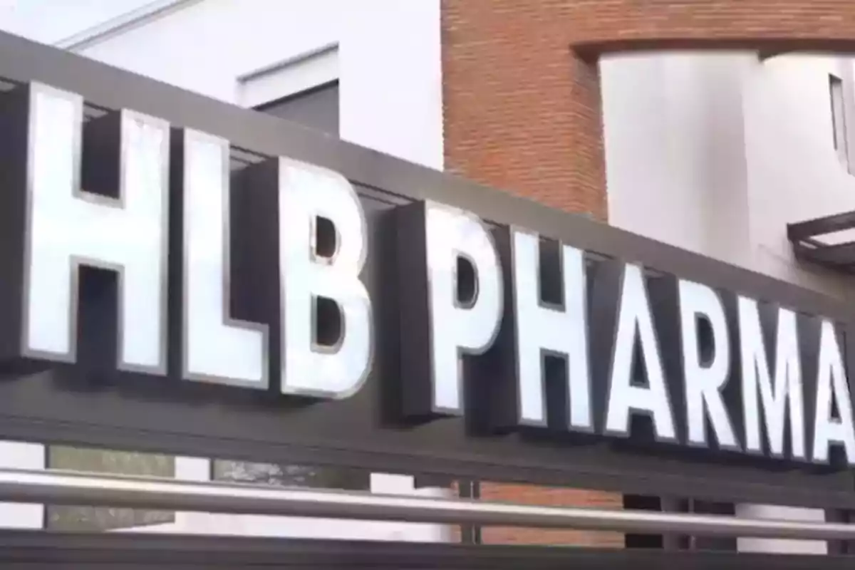 Illuminated sign of a pharmacy with the letters HLB PHARMA at the entrance of a modern building