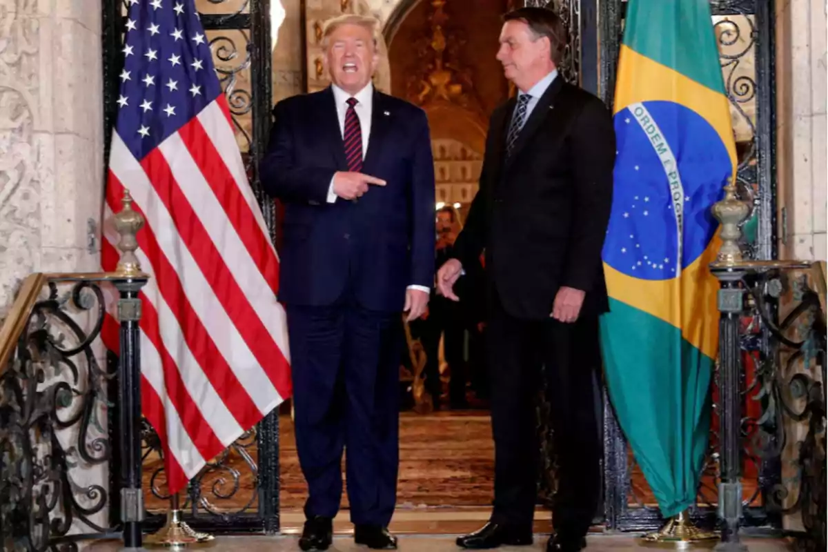 Dos hombres de traje posan frente a las banderas de Estados Unidos y Brasil en la entrada de un edificio elegante Dos hombres de traje posan frente a las banderas de Estados Unidos y Brasil en la entrada de un edificio elegante