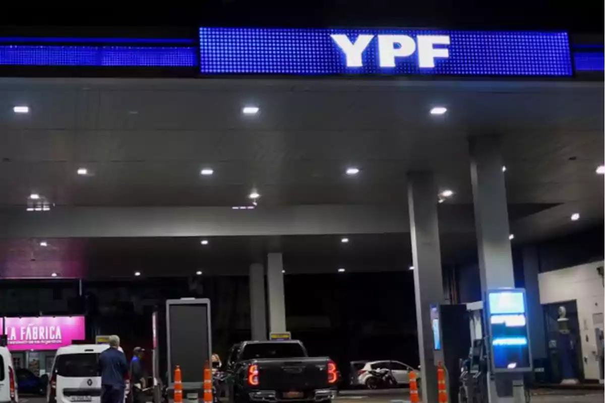 Estación de servicio YPF iluminada de noche con varios autos cargando combustible Estación de servicio YPF iluminada de noche con varios autos cargando combustible