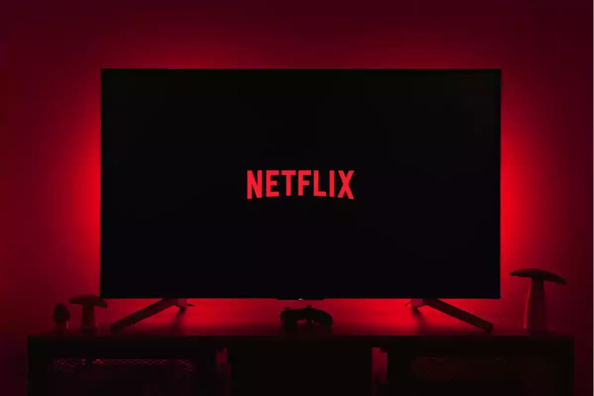 Television screen on with the Netflix logo in a room lit with red light Television screen on with the Netflix logo in a room lit with red light