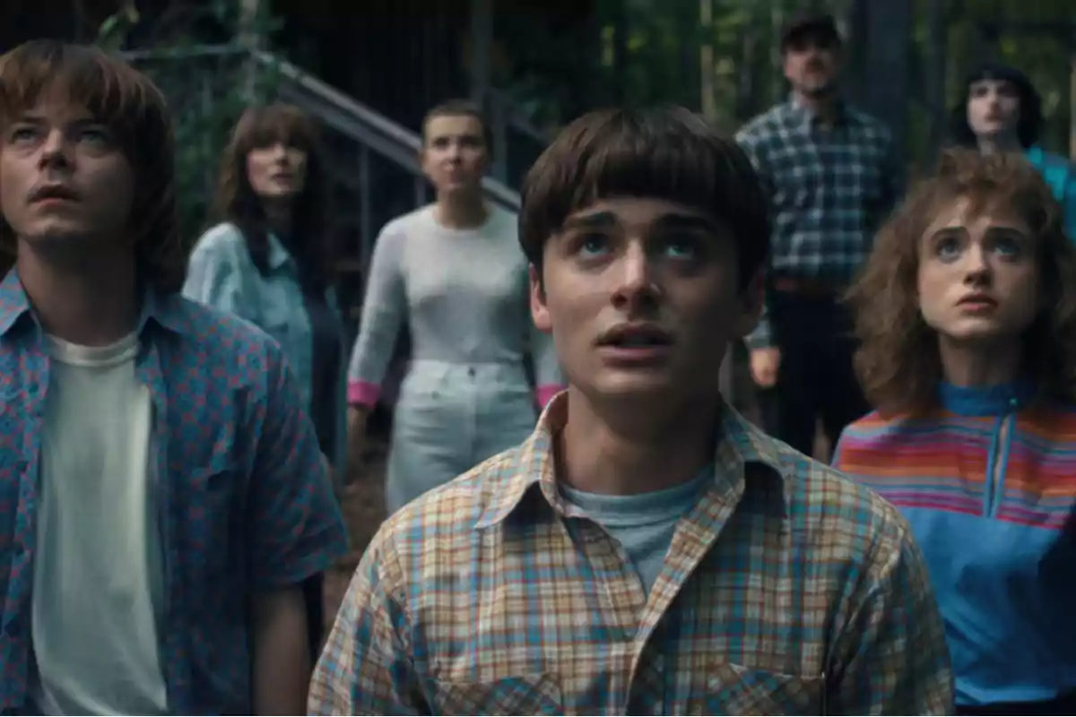 A group of young people and adults with expressions of amazement or concern look upward in an outdoor setting surrounded by trees. A group of young people and adults with expressions of amazement or concern look upward in an outdoor setting surrounded by trees.