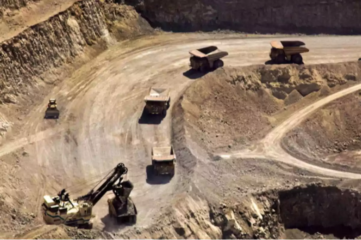 Aerial view of an open-pit mine with several haul trucks and an excavator working on the site. Aerial view of an open-pit mine with several haul trucks and an excavator working on the site.