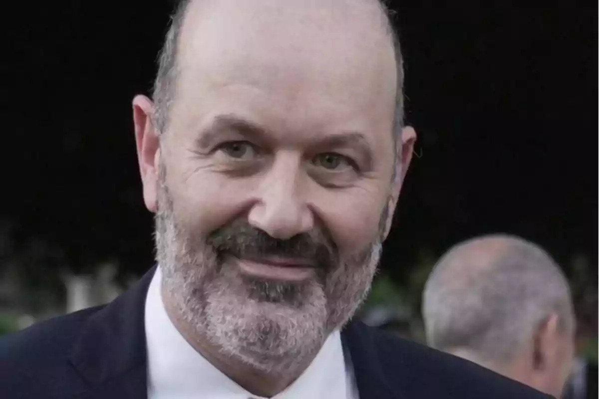 Middle-aged man with a beard and dark suit smiling outdoors Middle-aged man with a beard and dark suit smiling outdoors
