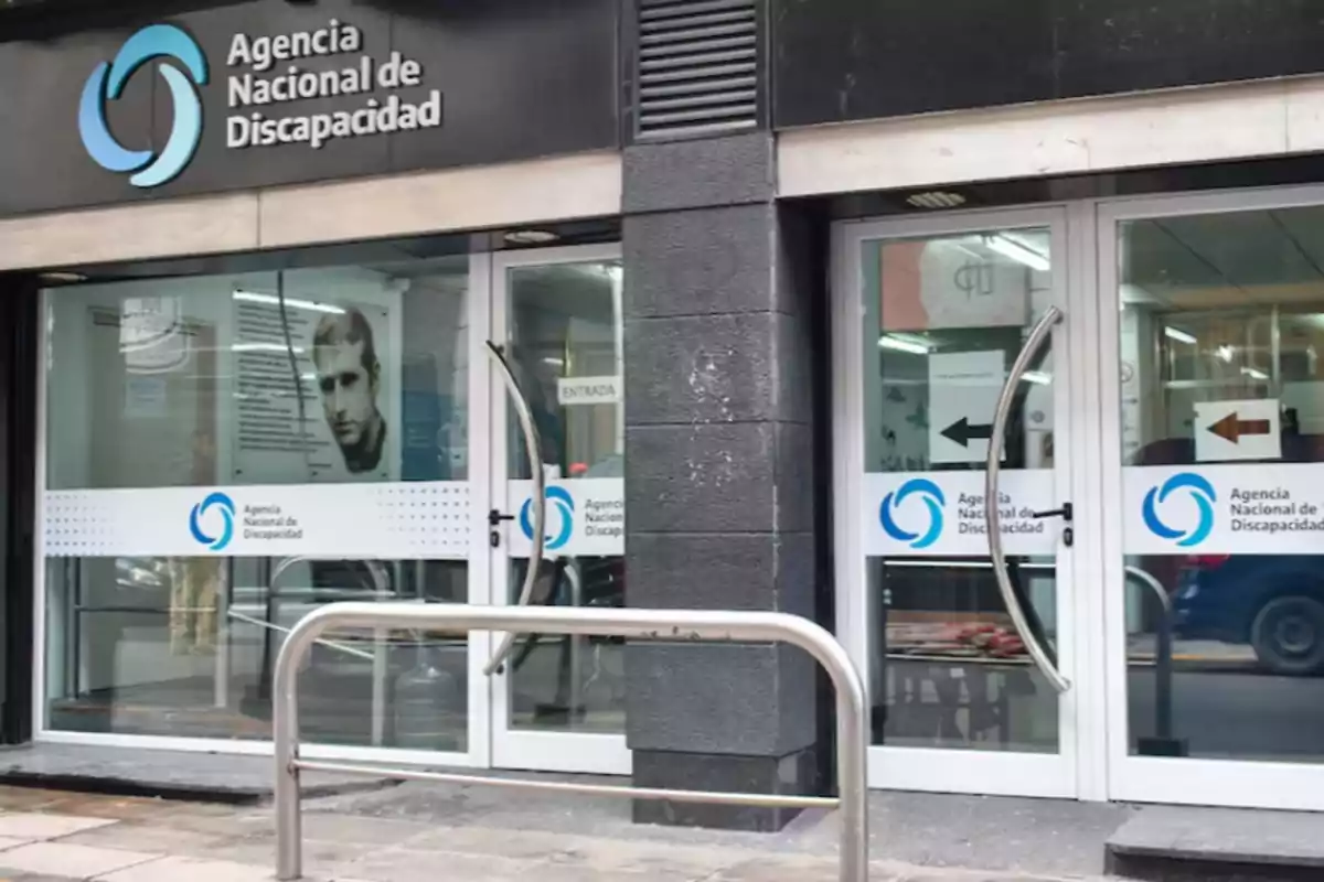 Fachada de la Agencia Nacional de Discapacidad con puertas de vidrio y carteles de entrada y salida Fachada de la Agencia Nacional de Discapacidad con puertas de vidrio y carteles de entrada y salida