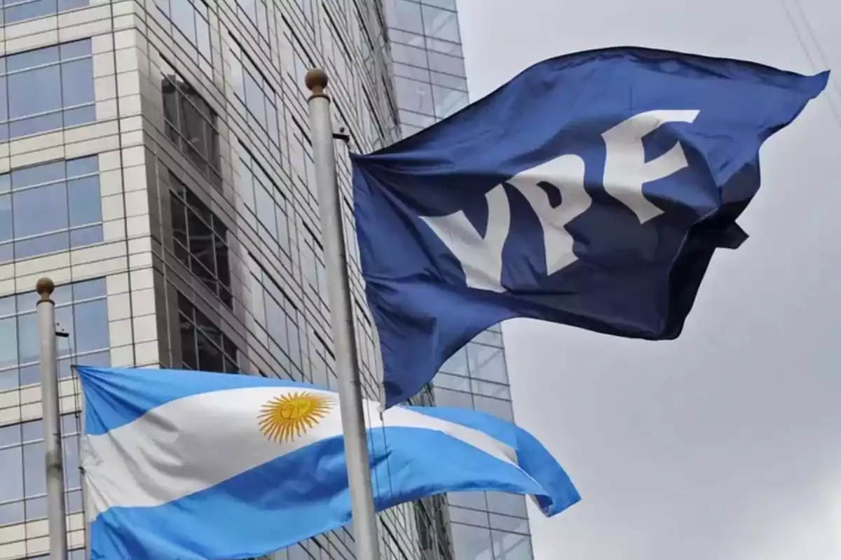 YPF and Argentine flags waving in front of a modern office building YPF and Argentine flags waving in front of a modern office building