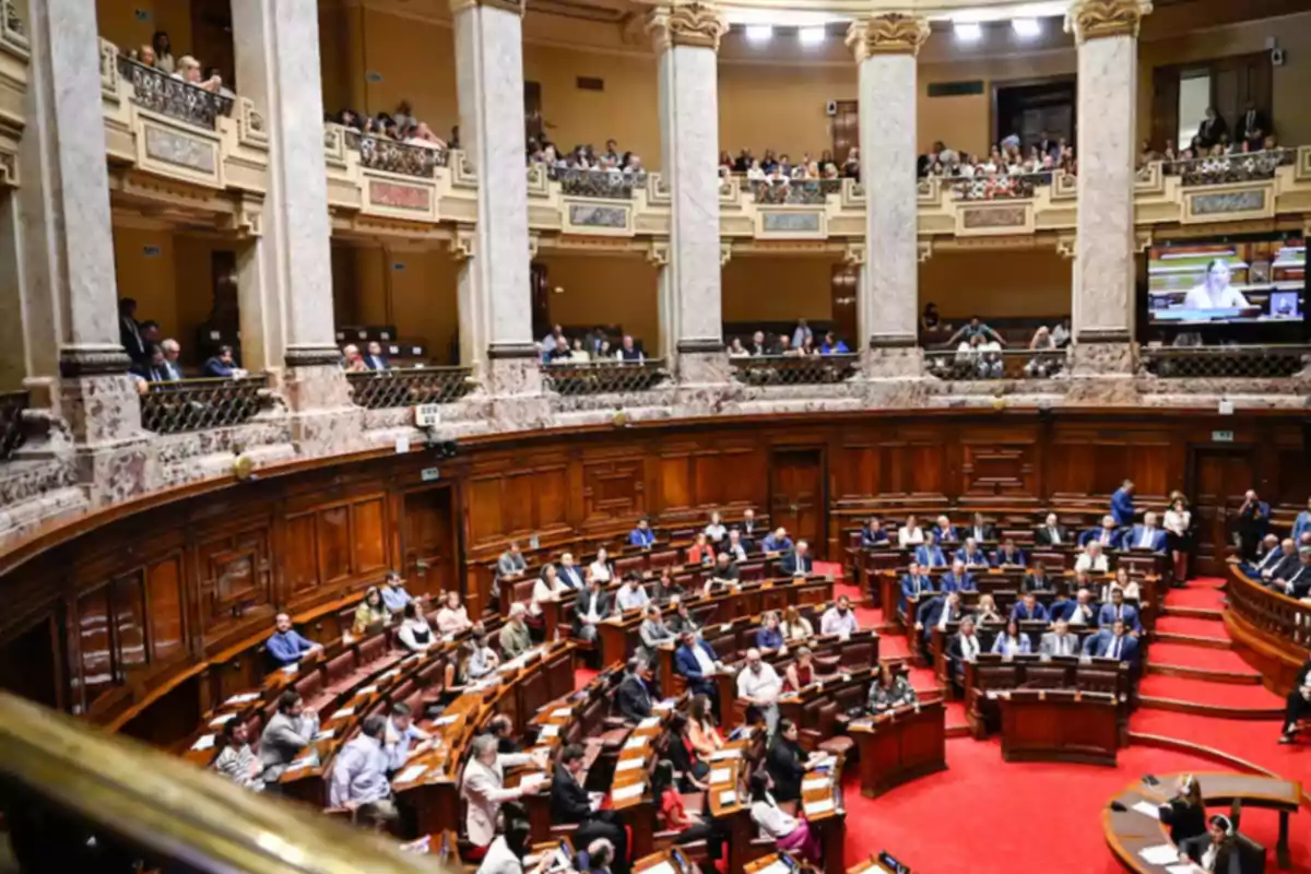 Vista de un parlamento con numerosos legisladores sentados en sus escaños y público observando desde los balcones en un edificio de arquitectura clásica