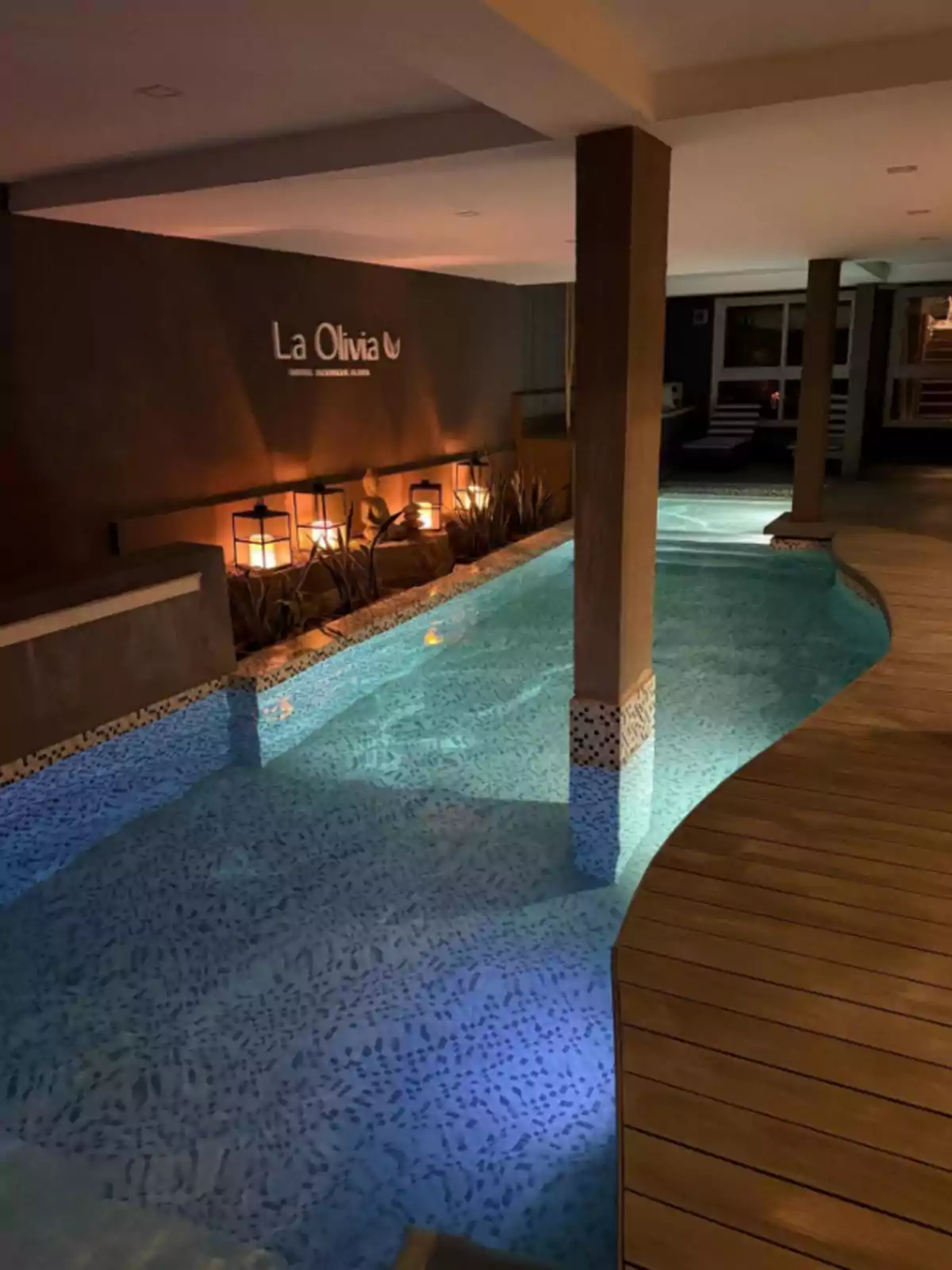 Piscina techada con iluminación tenue y decoración elegante en un hotel llamado La Olivia Piscina techada con iluminación tenue y decoración elegante en un hotel llamado La Olivia