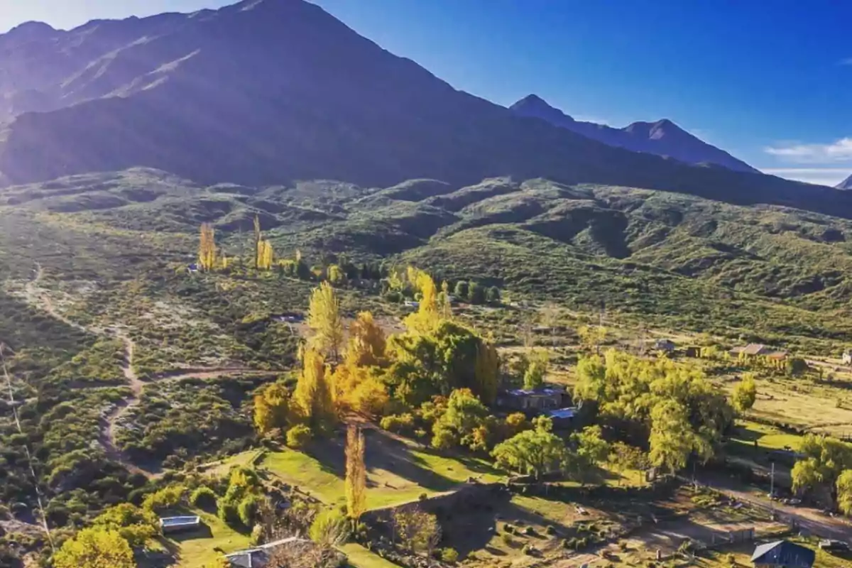 Mountain landscape with green hills and trees in autumn colors under a clear blue sky Mountain landscape with green hills and trees in autumn colors under a clear blue sky