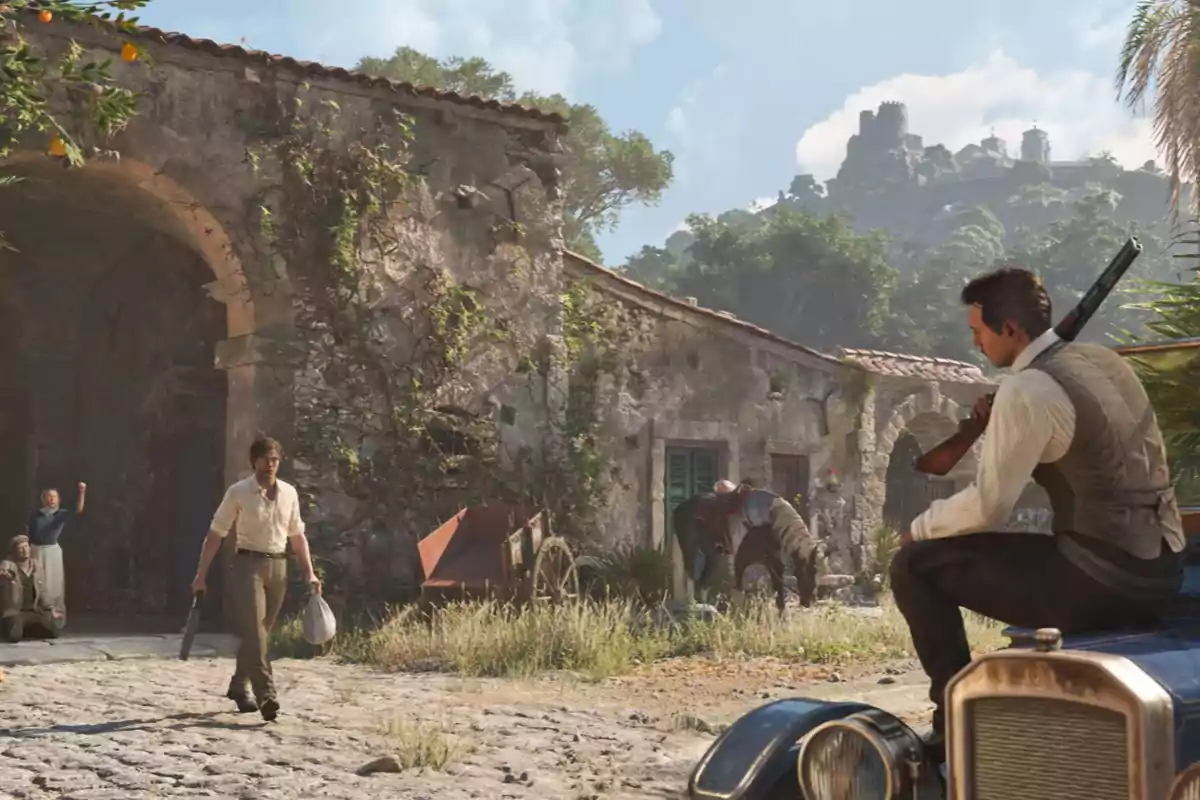 An armed man walks through an old village while another man with a shotgun watches, sitting on a classic car; in the background, there are people and a donkey next to a stone house covered in vegetation, and a fortress can be seen on the hill.