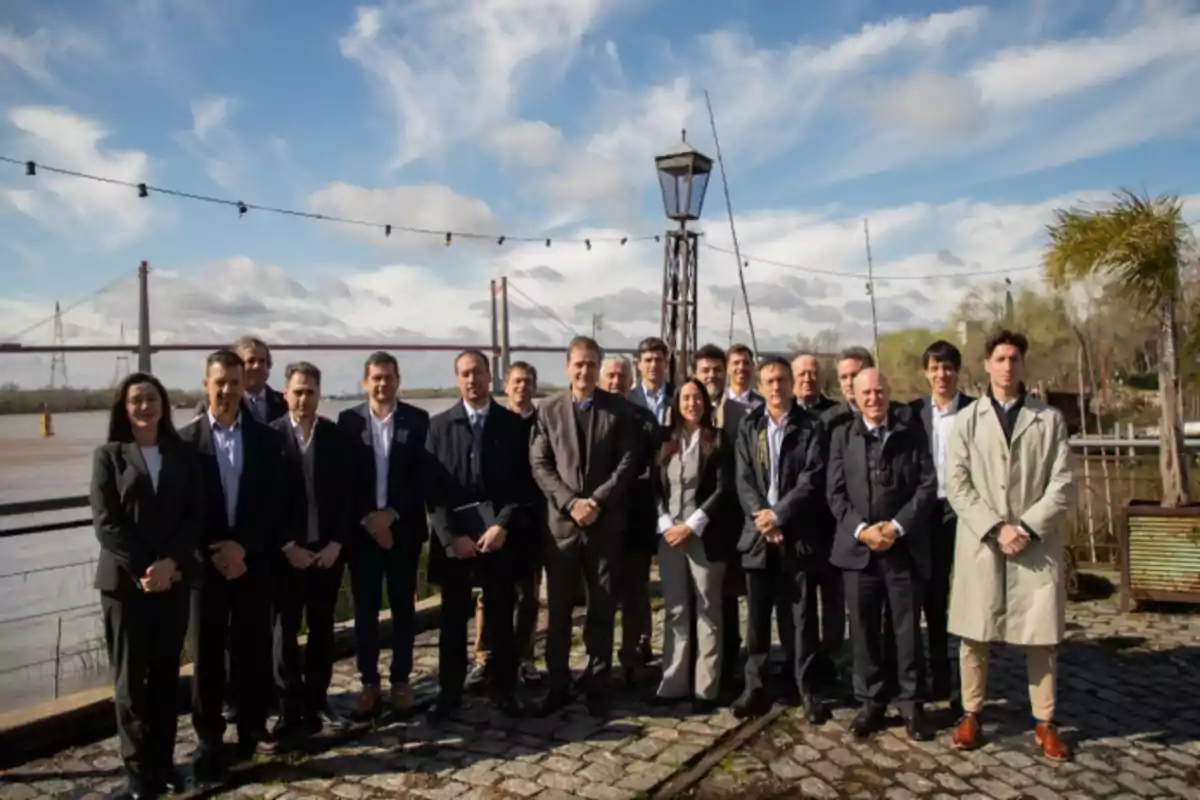 Group of people dressed formally posing outdoors in front of a river and a bridge on a sunny day Group of people dressed formally posing outdoors in front of a river and a bridge on a sunny day