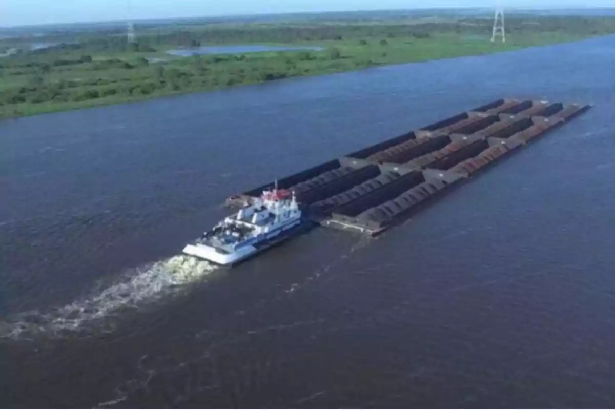 Barge carrying cargo on a wide river surrounded by vegetation Barge carrying cargo on a wide river surrounded by vegetation