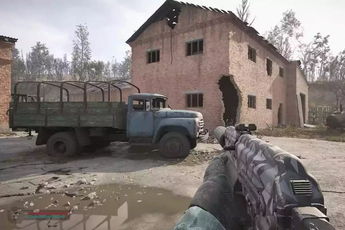 A rusty blue truck parked in front of a damaged brick building while a person holds a gun in the foreground in a video game setting. A rusty blue truck parked in front of a damaged brick building while a person holds a gun in the foreground in a video game setting.