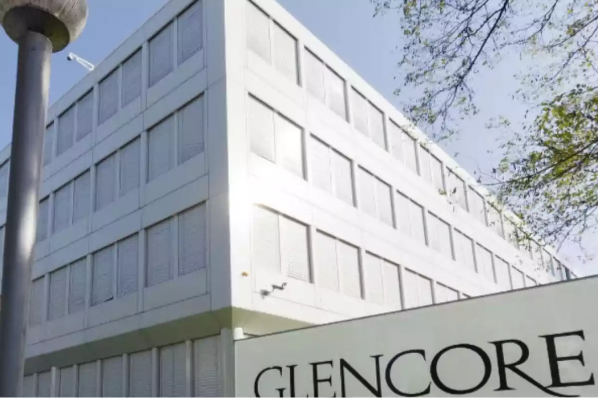 Modern multi-story building with closed windows and a sign in the foreground that says Glencore