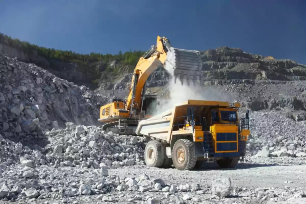 Excavator loading rocks into a dump truck at an open-pit mine Excavator loading rocks into a dump truck at an open-pit mine