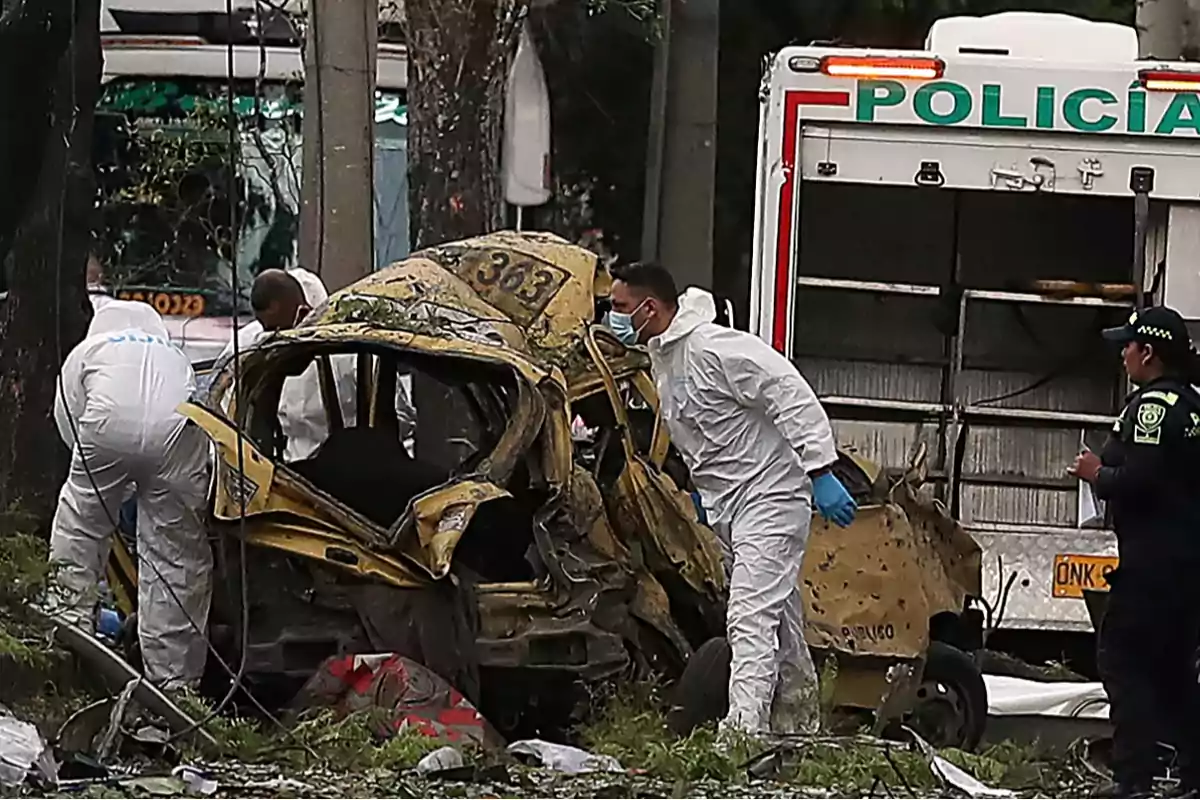 Peritos forenses y policías inspeccionan un taxi completamente destruido junto a una patrulla en una escena de accidente o crimen