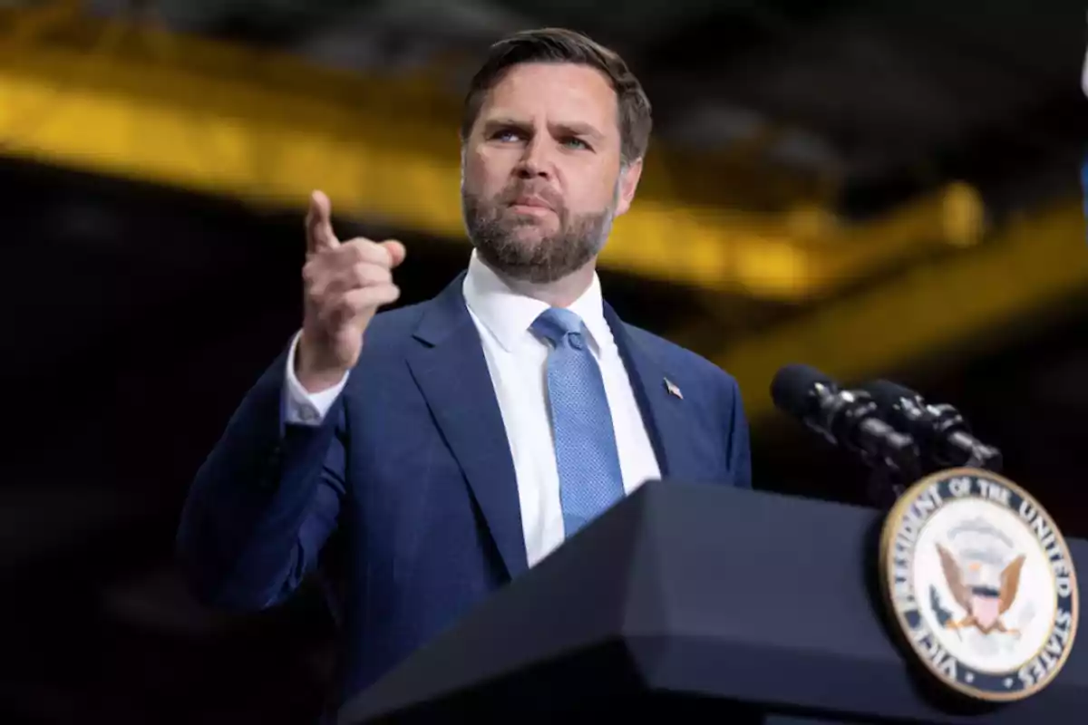 Man with a beard and a blue suit speaking at an official podium with the seal of the Vice Presidency of the United States while gesturing with his hand Man with a beard and a blue suit speaking at an official podium with the seal of the Vice Presidency of the United States while gesturing with his hand