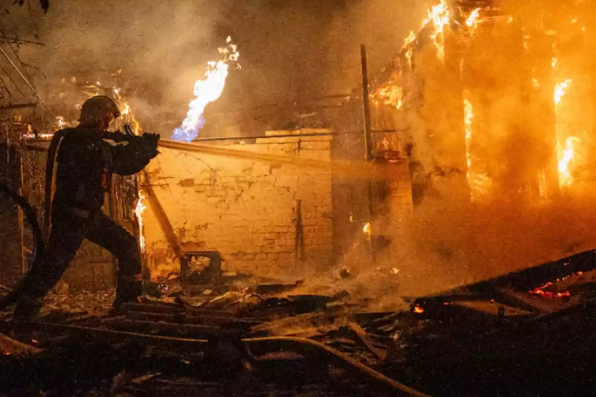 Firefighter battling a fire in a burning building at night