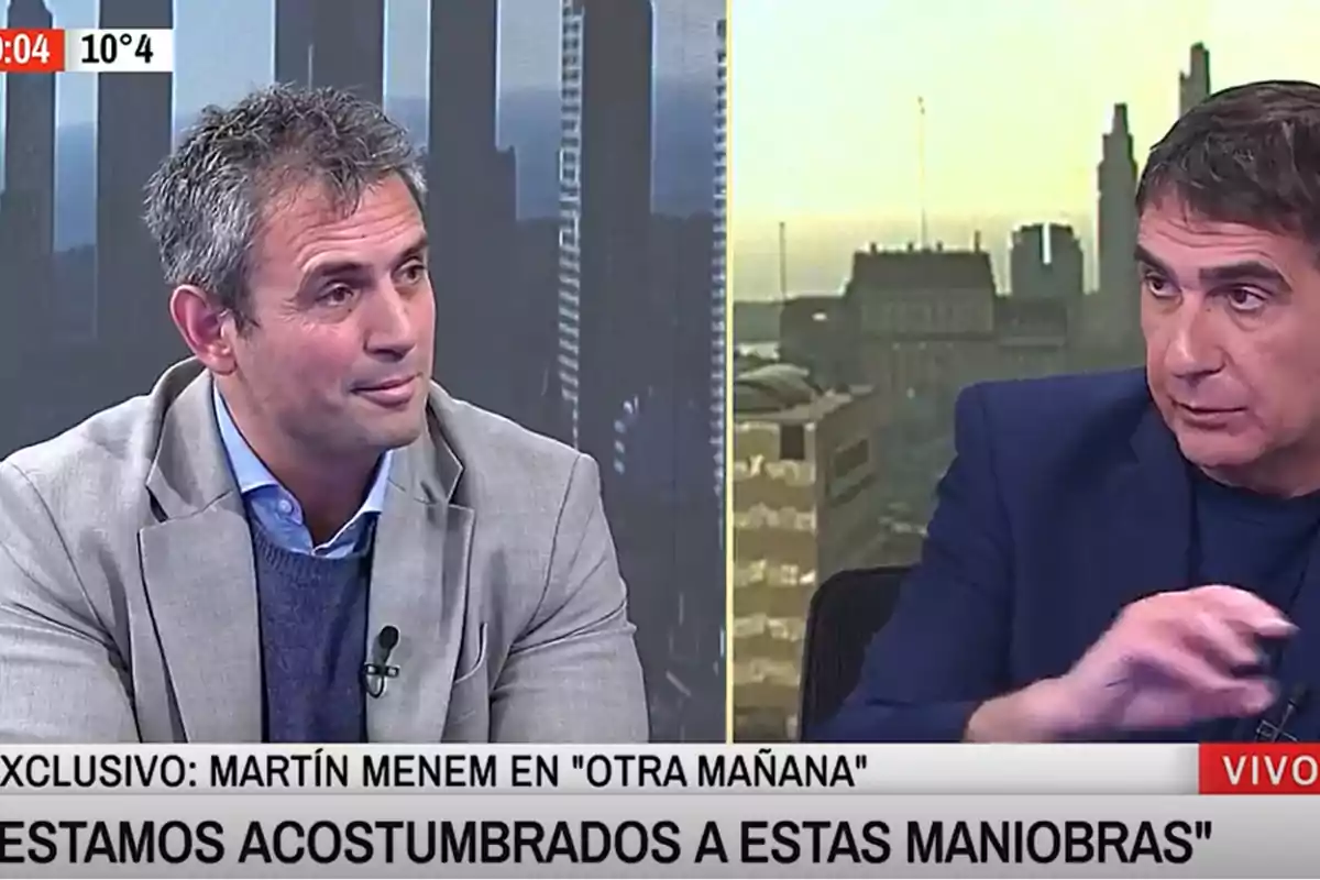 Two men are talking on a television show with a city background and a news ticker at the bottom of the screen. Two men are talking on a television show with a city background and a news ticker at the bottom of the screen.