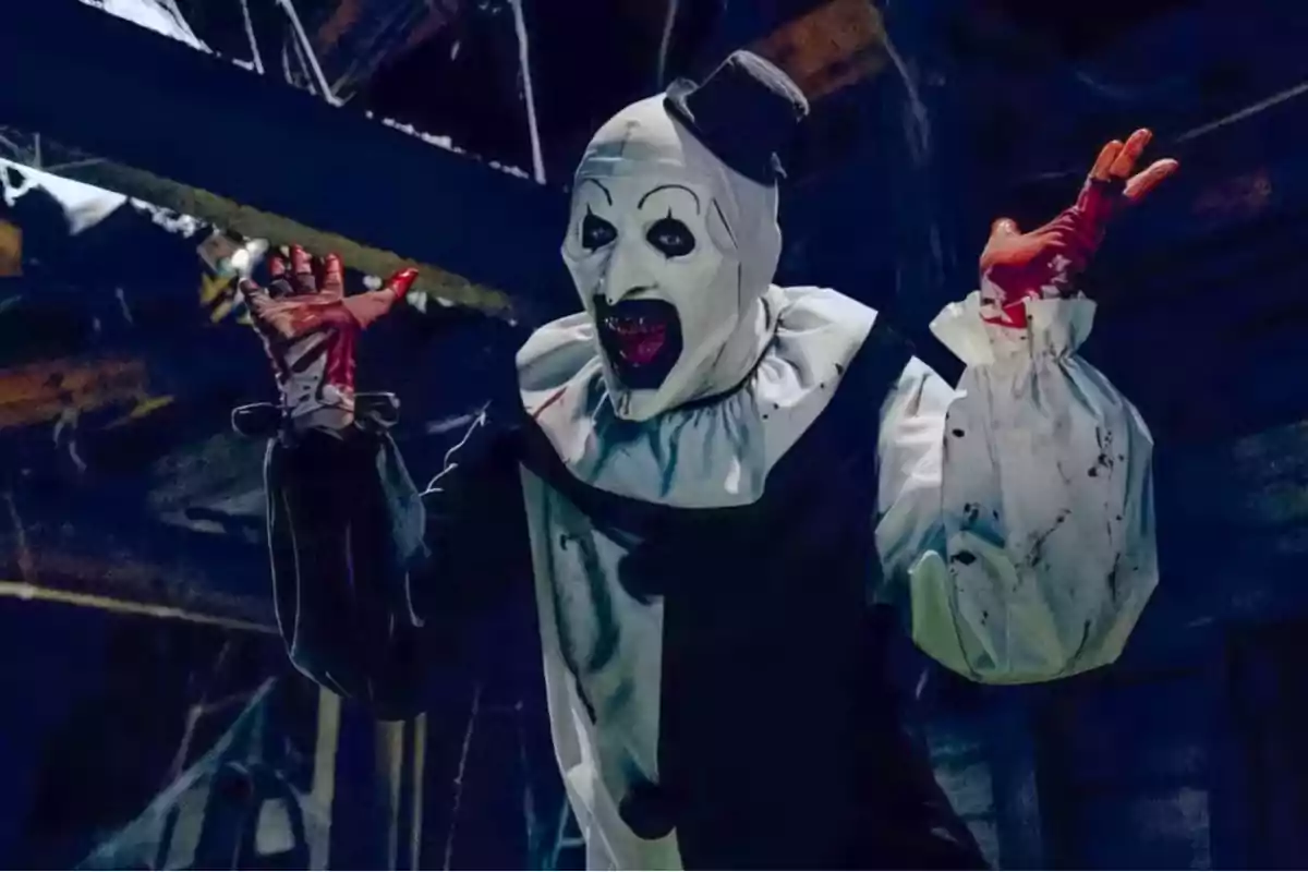 Payaso aterrador con maquillaje blanco y negro, guantes ensangrentados y expresión amenazante en un ambiente oscuro