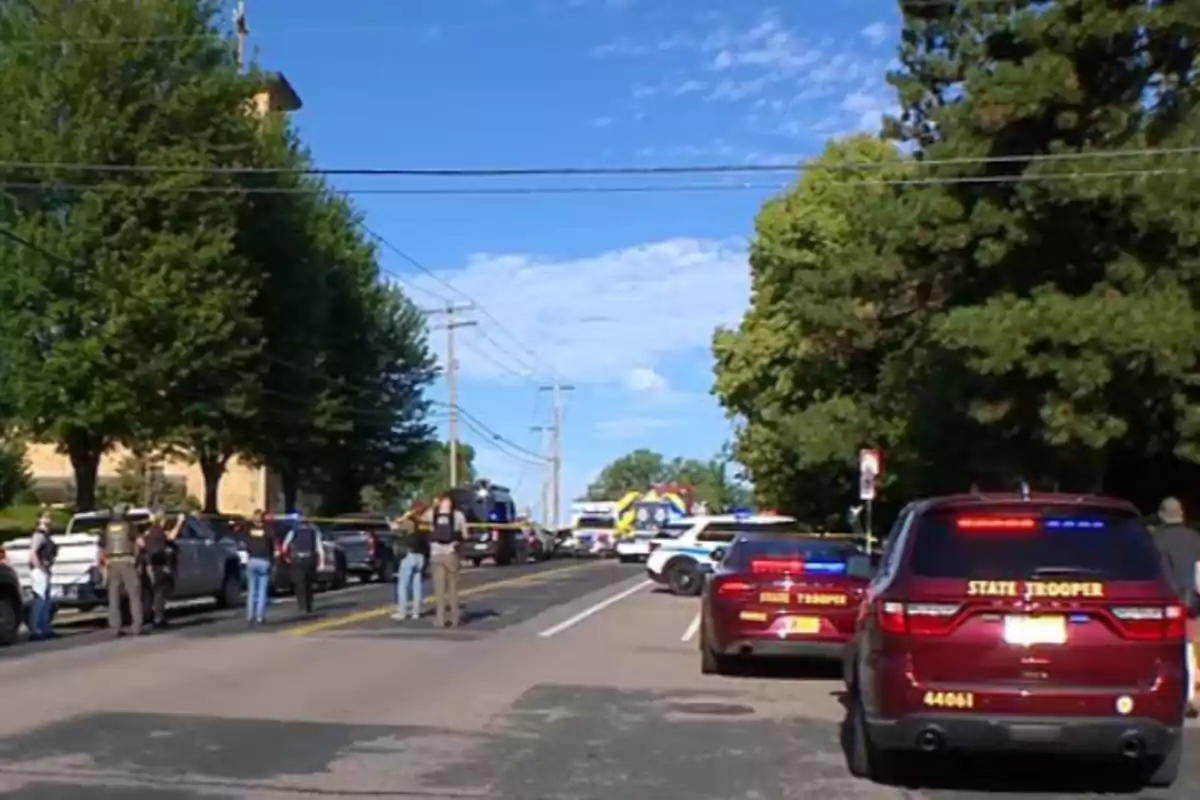 Varios autos de policía y agentes bloquean una calle rodeada de árboles durante un operativo bajo un cielo despejado. Varios autos de policía y agentes bloquean una calle rodeada de árboles durante un operativo bajo un cielo despejado.