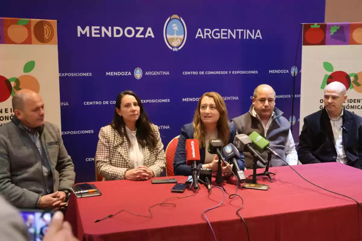Cinco personas sentadas en una mesa con micrófonos en una conferencia de prensa en Mendoza, Argentina, con un fondo azul que tiene el nombre de la ciudad y el país. Cinco personas sentadas en una mesa con micrófonos en una conferencia de prensa en Mendoza, Argentina, con un fondo azul que tiene el nombre de la ciudad y el país.