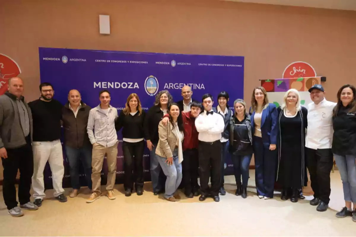 Grupo de personas posando juntas frente a un cartel azul que dice Mendoza Argentina en un evento en interiores Grupo de personas posando juntas frente a un cartel azul que dice Mendoza Argentina en un evento en interiores