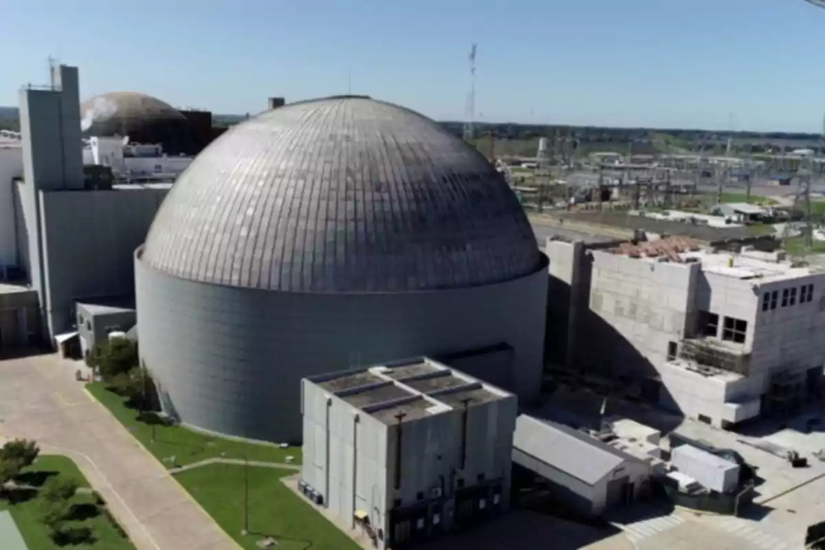 Aerial view of a nuclear power plant with a large metal dome and industrial buildings around it in a clear environment Aerial view of a nuclear power plant with a large metal dome and industrial buildings around it in a clear environment