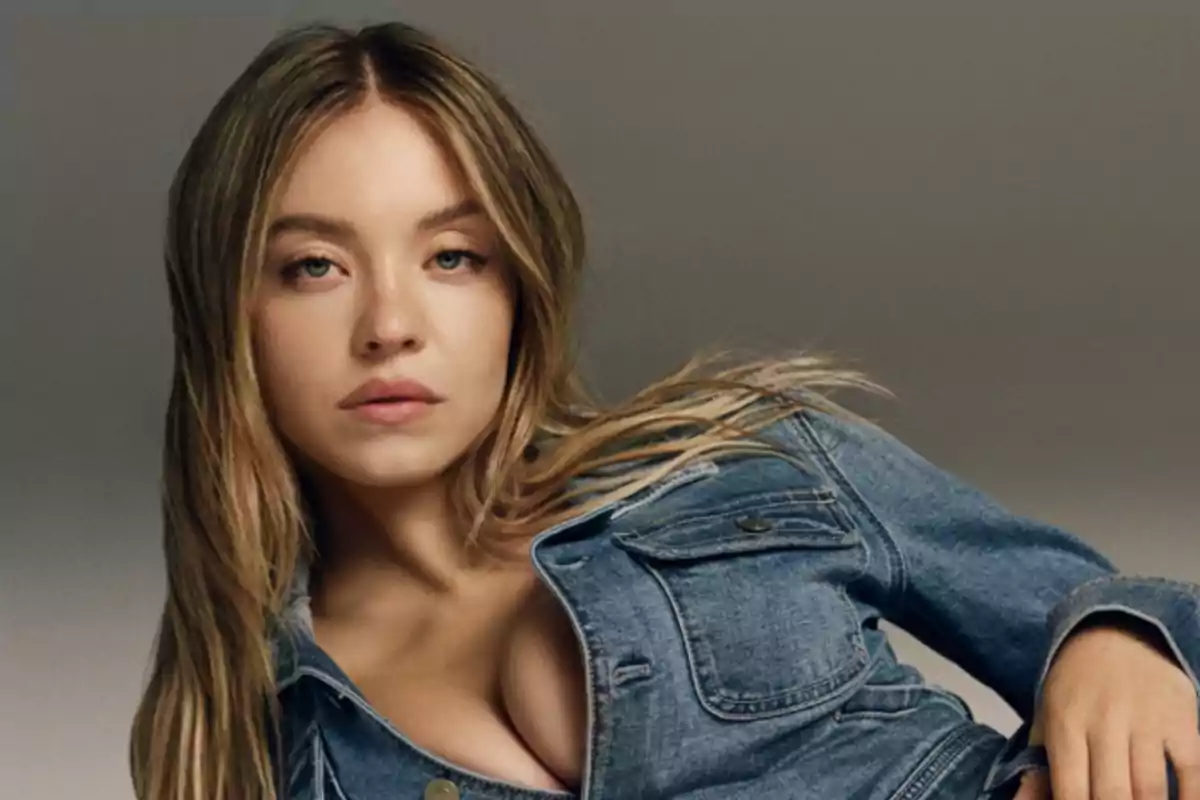 Mujer joven con cabello rubio largo usando chaqueta de mezclilla y mirando a la cámara Mujer joven con cabello rubio largo usando chaqueta de mezclilla y mirando a la cámara