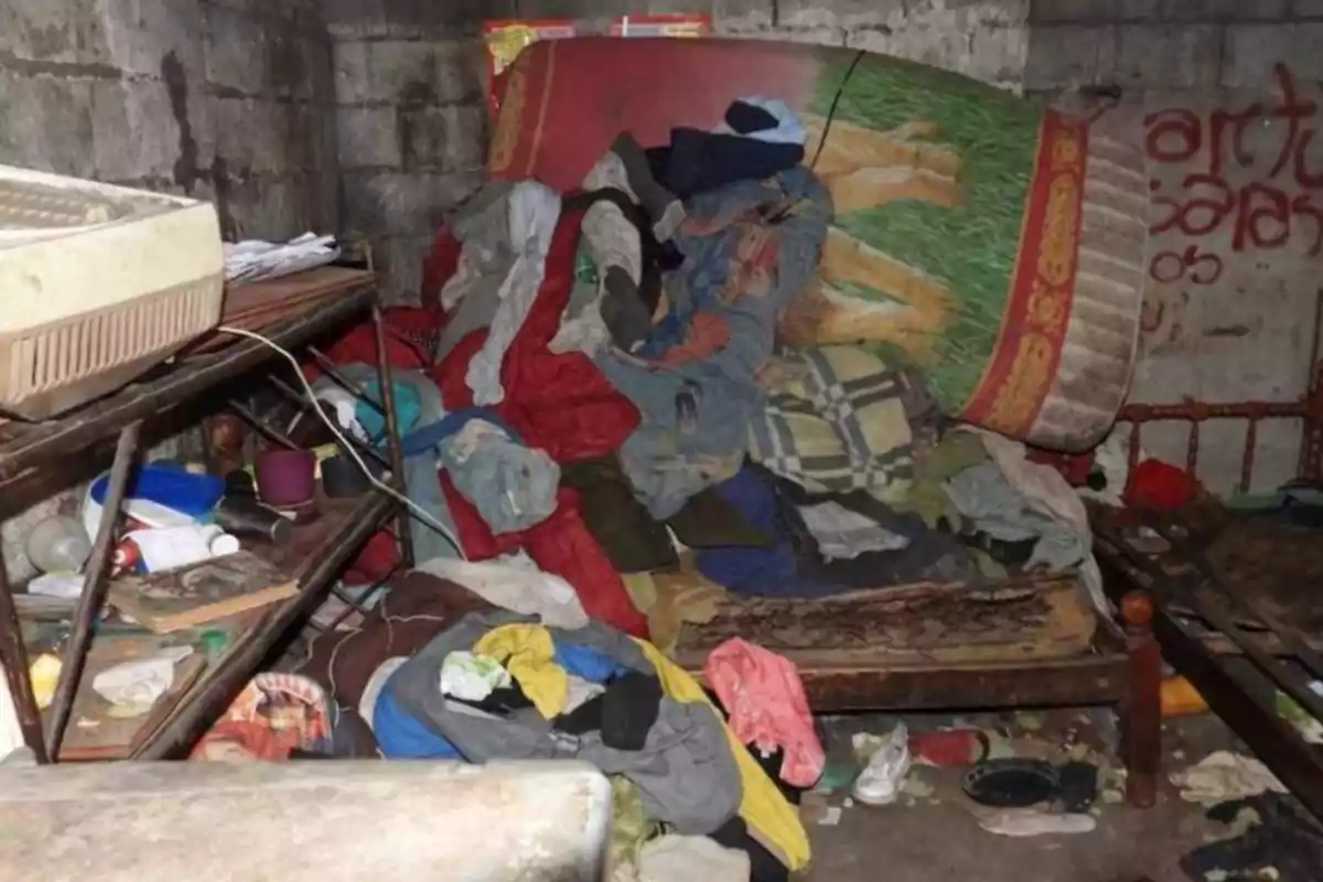Messy room with clothes and objects scattered on a bed and the floor, block walls, and a shelf full of stuff. Messy room with clothes and objects scattered on a bed and the floor, block walls, and a shelf full of stuff.