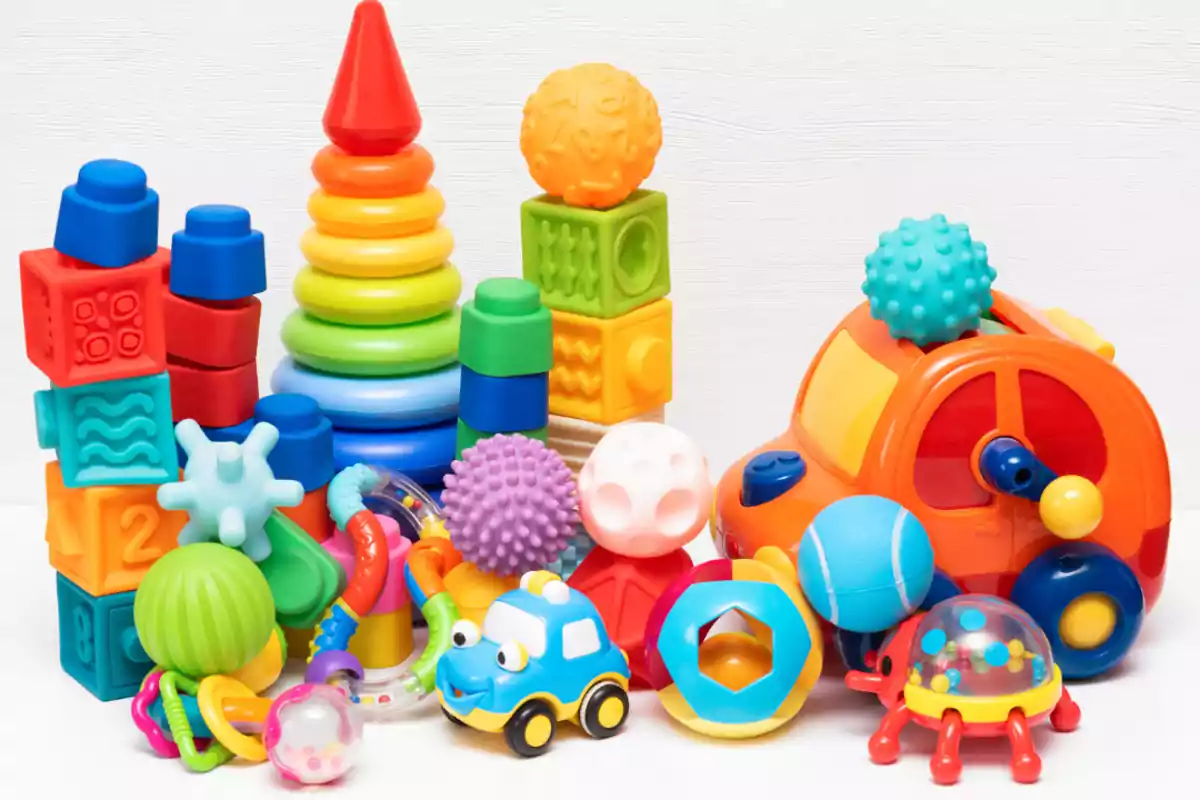 Juguetes coloridos para bebés y niños pequeños incluyendo bloques, aros apilables, pelotas, sonajas y un carro de juguete Juguetes coloridos para bebés y niños pequeños incluyendo bloques, aros apilables, pelotas, sonajas y un carro de juguete