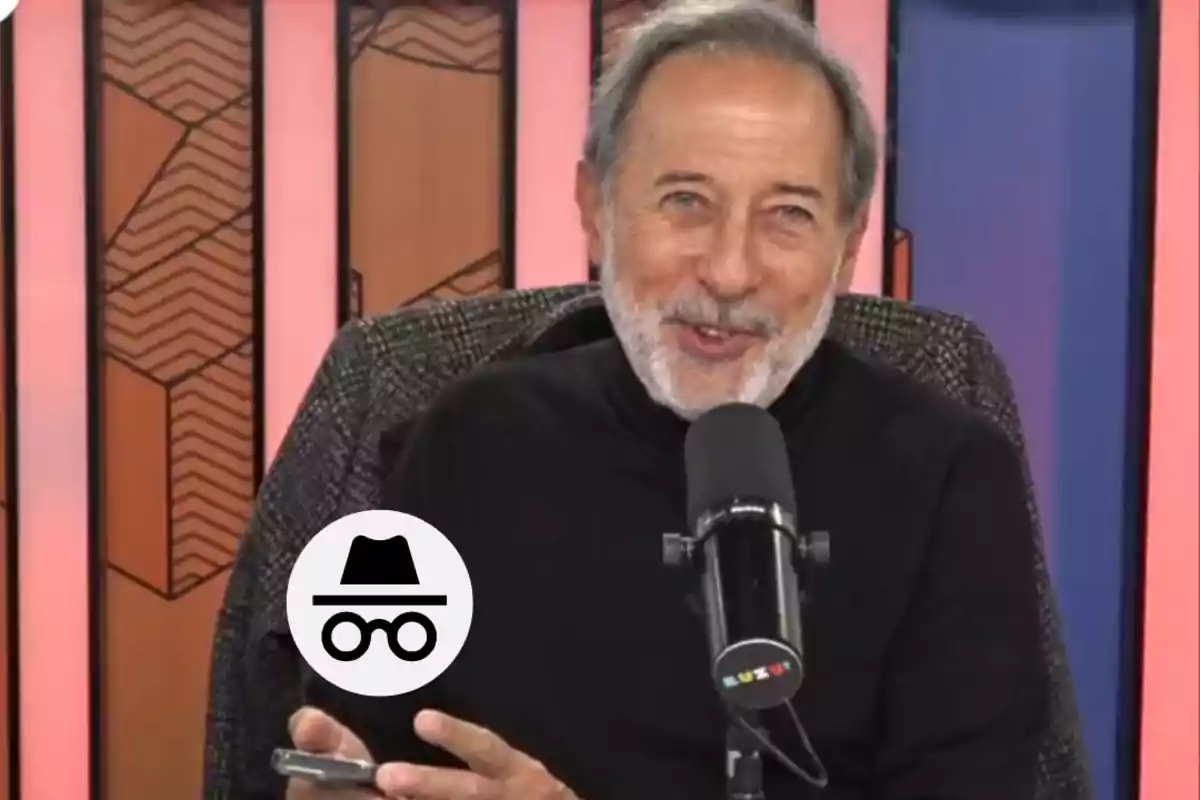 Gray-haired man with a beard smiling in front of a microphone, with a colorful background and an incognito icon in the lower left corner